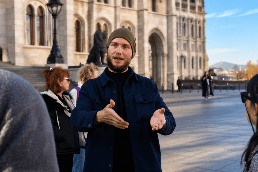 Guide gesturing to travelers outside Budapest Parliament building