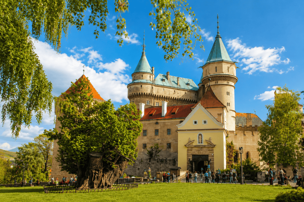 Visitors gathering at Bojnice Castle entrance beside ancient linden tree