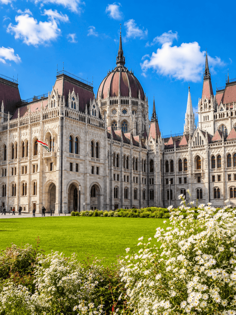 Hungarian Parliament facade in Budapest behind blooming flowers