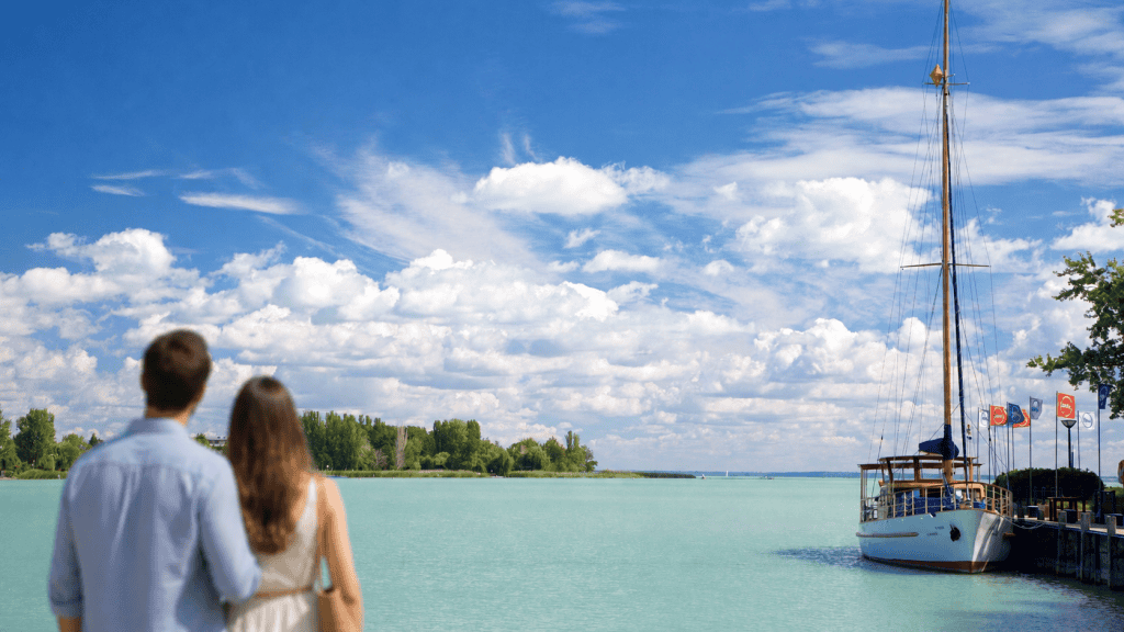 Couple watching a sailboat on turquoise Lake Balaton