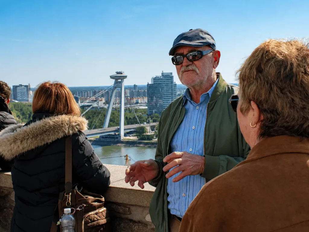Guide talking to travelers above Bratislava with UFO bridge behind